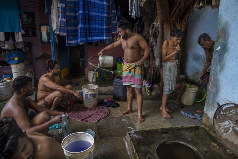 Migrant workers wash their clothes near a well which serves as a bathing area outside their rented accommodations in Dharavi, one of Asia's largest slums, in Mumbai, India, Wednesday, May 3, 2023. (AP Photo/Dar Yasin)