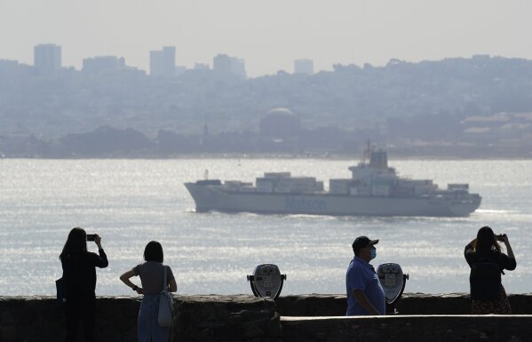 People stand at a vista point and look out toward the the San Francisco skyline obscured by smoke from wildfires as a container ship passes Monday, Sept. 28, 2020, near Sausalito, Calif. (AP Photo/Eric Risberg)