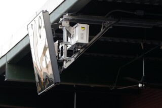FILE - A radar device is seen on the roof behind home plate at PeoplesBank Park during the third inning of an Atlantic League All-Star minor league baseball game in York, Pa. Baseball's top minor leagues are switching to a challenge system full-time for their test of robot umpires. Major League Baseball has been experimenting with the automated ball-strike system in the minor leagues since 2019. (AP Photo/Julio Cortez, File)