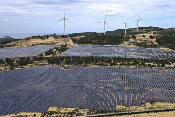 Solar panels work near wind turbines in Quy Non, Vietnam on June 11, 2023. Vietnam has released a long-anticipated energy plan meant to take the country through the next decade and help meet soaring demand while reducing carbon emissions. (AP Photo/Minh Hoang)