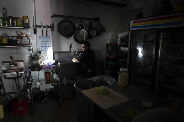 FILE - Workers at Las Palmas Cafe work with the power of an electricity generator during an island-wide blackout, in San Juan, Puerto Rico, April 7, 2022. (AP Photo/Carlos Giusti, File)