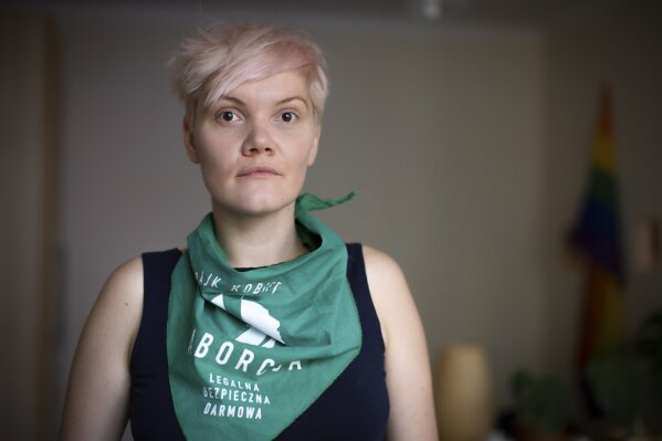 Polish actress and singer Karolina Micula poses for a portrait wearing a scarf thet reads "Women's Strike - Safe, Free, Legal Abortion" in Warsaw, Poland, Wednesday, Nov. 18, 2020. When Poland's right-wing government first tried to restrict abortion rights, the actress and singer delivered an intense performance onstage in Wroclaw in 2017 that included her spreading paint in the national colors — white and red — onto her breasts and face, ending with a fist raised high. (AP Photo/Agata Grzybowska)