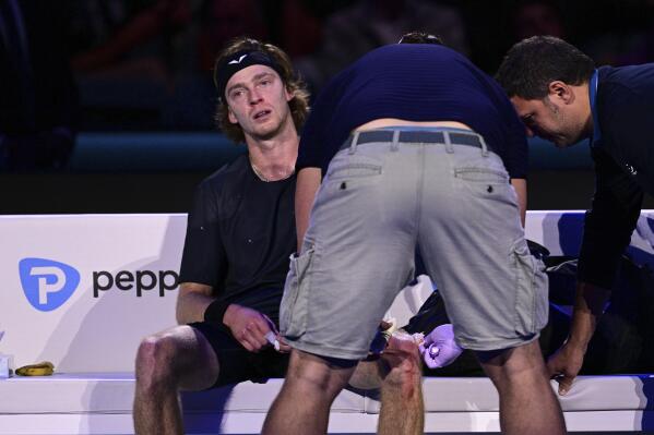 Andrey Rublev receives medical attention after he grew so frustrated during a 7-5, 6-2 loss to Carlos Alcaraz at the ATP World Tour Finals at the Pala Alpitour, in Turin, Italy, Wednesday, Nov. 15, 2023, that he repeatedly hit himself with his racket so hard that he bloodied his left knee. (Marco Alpozzi/LaPresse via AP)