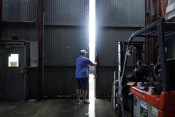 Jarod Voisin closes the doors of his family's heavily damaged oyster processing plant, as rain from Tropical Storm Nicholas, currently in the Gulf of Mexico, comes down, in the aftermath of Hurricane Ida in Houma, La., Tuesday, Sept. 14, 2021. (AP Photo/Gerald Herbert)