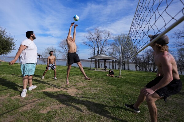 FILE - Edgar Portillo, center, goes up for a hit while playing volleyball with friends Aaron Sanchez Jr., left, Julio Nunez, second from left, and Vance Rabozzi, right, during a warm winter day along the shore of Joe Pool Lake, Feb. 26, 2024, in Grand Prairie, Texas. Earth has exceeded global heat records in February, according to the European Union climate agency Copernicus. (AP Photo/Julio Cortez, File)