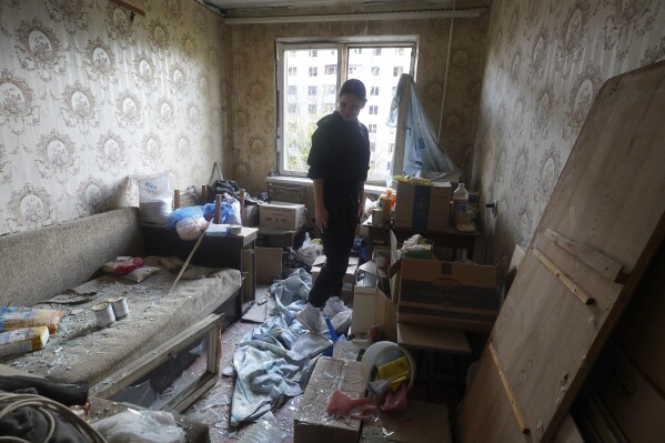 A woman stands inside her apartment damaged by a Russian strike in Kharkiv, Ukraine, Friday April 18, 2025. (AP Photo/Andrii Marienko)