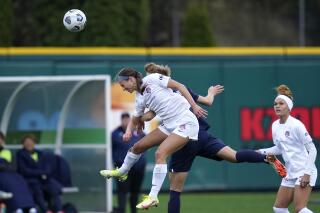 Washington Spirit forward Ashley Hatch, left, heads the ball in front of OL Reign midfielder Quinn in the second half in the semifinals of the NWSL soccer playoffs Sunday, Nov. 14, 2021, in Tacoma, Wash. (AP Photo/Elaine Thompson)