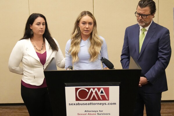 FILE - Tennis player Kylie McKenzie, middle, with her attorney Robert Allard, right, and victim advocate Jancy Thompson, left, speaks to reporters at a news conference in Phoenix Tuesday, March 29, 2022. McKenzie has been awarded $9 million in damages by a jury in federal court in Florida after accusing the U.S. Tennis Association of failing to protect her from a coach she said sexually abused her at one of its training centers when she was a teenager. “I couldn’t be happier with the outcome. I feel validated,” McKenzie said in a statement emailed Tuesday, May 7, 2024, by one of her lawyers, Amy Judkins. (Michael Chow/The Arizona Republic via AP, File)