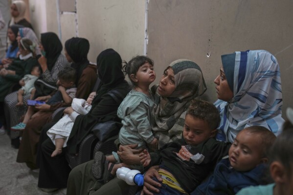 Palestinian women wait with their sick children for medical care in an overcrowded clinic in Gaza City, Wednesday, May 28, 2025. (AP Photo/Jehand Alshrafi)