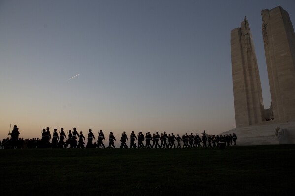 FILE- Canadian soldiers march at a sunset ceremony and mounting of the vigil at the WWI Canadian National Vimy Memorial in Givenchy-en-Gohelle, France on April 8, 2017. With war ravaging Europe's heartland again, the countless headstones, cemeteries and memorials from World War I are a timeless testimony to its cruelty. Belgium and France want them recognized as UNESCO World Heritage sites to make sure people stop and think. (AP Photo/Virginia Mayo, File)