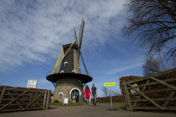 
              A couple of voters leaves the Kerkhovense Molen, a windmill turned polling station in Oisterwijk, south central Netherlands, Wednesday, March 15, 2017. Amid unprecedented international attention, the Dutch go to the polls Wednesday in a parliamentary election that is seen as a bellwether for the future of populism in a year of crucial votes in Europe. The sign at right reads "polling station" (AP Photo/Peter Dejong)
            