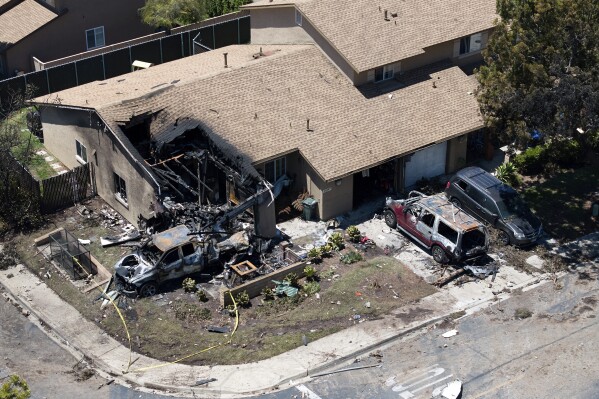 Debris covers the ground after a small plane crashed into a San Diego neighborhood, setting homes and cars on fire and forcing evacuations early Thursday, May 22, 2025. (AP Photo/William Liang)