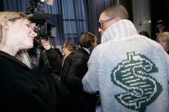 FILE - U.S rap artist Pharrell Williams, right, talks with an unidentified journalist after the presentation of Louis Vuitton men's fall/winter 2008-2009 fashion collection in Paris, Jan.17, 2008. The signs of hip-hop’s influence are now everywhere from Pharrell Williams becoming Louis Vuitton’s men’s creative director to billion-dollar brands like Dr. Dre’s Beats headphones and retail mainstays like Diddy’s Sean John and the Rocawear line started by Jay-Z. It didn’t start out that way. Companies at first balked at partnering with hip-hop acts because they felt that the genre that appealed to Black and brown teens and young adults didn't align with their brands. (AP Photo/Thibault Camus, file)