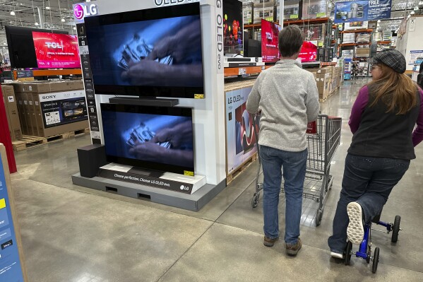 Shoppers pass by large-screen televisions on display in a Costco warehouse Thursday, Dec. 19, 2024, in Colorado Springs, Colo. (AP Photo/David Zalubowski, File)