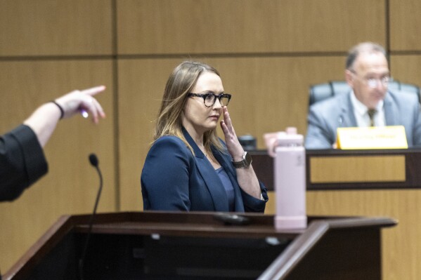 Cobb County teacher Katie Rinderle walks to the stand to testify during a hearing at the Cobb County Board of Education in Marietta, Ga, Thursday, Aug. 10, 2023. Rinderle is facing termination after reading "My Shadow is Purple," a book about gender identity, to fifth graders. (Arvin Temkar/Atlanta Journal-Constitution via AP)