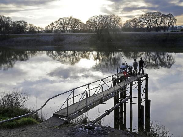 FILE - In this Feb. 23, 2016, file photo, people try to catch fish along the Sacramento River in the San Joaquin-Sacramento River Delta, near Courtland, Calif. On Tuesday, March 29, 2022, California Gov. Gavin Newsom announced some of the state's largest water agencies have agreed to let more water flow through the state's major rivers and streams. The extra water will benefit the state's endangered species of salmon. But environmental groups say they were left out of the negotiations and the new agreement does not go far enough. (AP Photo/Rich Pedroncelli, File)