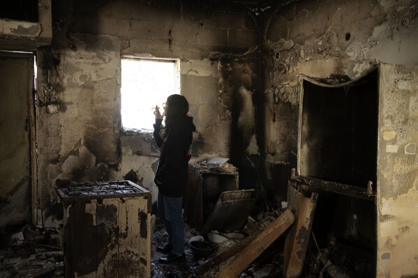 Sharon Alony Cunio surveys the kitchen in the ruins of her home in Kibbutz Nir Oz on Monday, Jan. 15, 2024. Cunio, her husband and their 3-year-old twin daughters were kidnapped from the home by Hamas militants on Oct. 7, 2023. She and her daughters were released in November, but her husband remains in captivity. (AP Photo/Maya Alleruzzo)