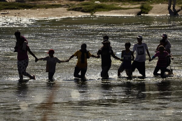 Migrantes forman una cadena humana para cruzar el Río Bravo desde México a Estados Unidos, el 21 de septiembre de 2023, en Eagle Pass, Texas. (AP Foto/Eric Gay)