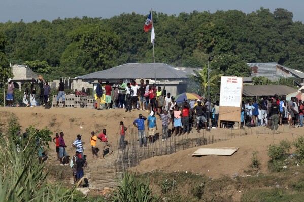 People stand near the construction of a canal, on the bank of the Massacre River, a natural border between Haiti and the Dominican Republic, photographed from Dajabon, Dominican Republic, Friday, Sept. 15, 2023. The Dominican Republic shut all land, air and sea borders with Haiti on Friday in a dispute about construction of a canal on Haitian soil that taps into the shared river. (AP Photo/Ricardo Hernandez)