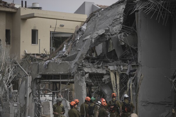 Israel's home front command officers survey the site where a missile launched from Iran struck in Nes Ziona ,Israel, Sunday, June 22, 2025. (AP Photo/Ohad Zwigenberg)