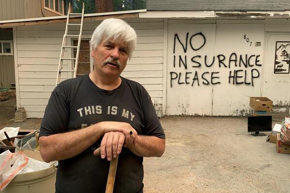 Tod Johnson stands in front of his house in South Lake Tahoe, Calif., on Tuesday, Aug. 31, 2021, a day after the city was ordered to evacuate because of the fast-growing Caldor Fire. He spray-painted his house, which is not insured, hoping that firefighters would help save it if the fire reaches his neighborhood. (AP Photo/Terry Chea)