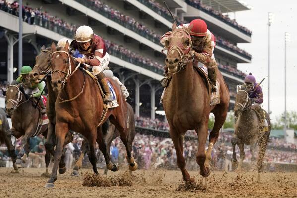 Sonny Leon rides Rich Strike, center, across the finish line to win the 148th running of the Kentucky Derby horse race at Churchill Downs Saturday, May 7, 2022, in Louisville, Ky. (AP Photo/Jeff Roberson)