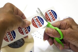 FILE - A precinct worker in Jackson, Miss., cuts individual "I Voted in Hinds County" stickers on Aug. 8, 2023. Election officials in Mississippi's most populous county had to scramble to complete required poll worker training after an early September breach involving county computers. (AP Photo/Rogelio V. Solis, File)