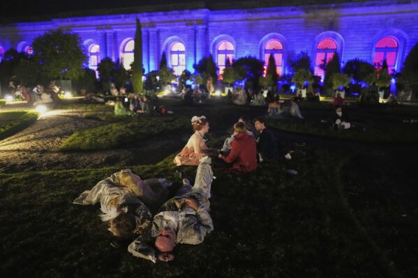 Costumed guests take a break as they attend the Great Masked Ball in the Orangerie of the Versailles castle, outside Paris, Sunday, June 22, 2025. (AP Photo/Christophe Ena)