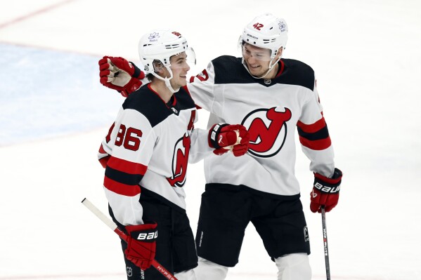 New Jersey Devils forward Jack Hughes, left, celebrates his third goal of an NHL hockey game against the Columbus Blue Jackets with teammate forward Curtis Lazar during the third period in Columbus, Ohio, Saturday, Dec. 16, 2023. (AP Photo/Paul Vernon)