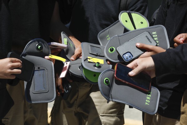 A student uses their cell phone after unlocking the pouch that secures it from use during the school day at Bayside Academy, Friday, Aug. 16, 2024, in San Mateo, Calif. (Lea Suzuki/San Francisco Chronicle via AP, File)