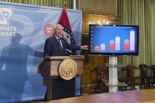 FILE - In this July 29, 2021 file photo, Arkansas Gov. Asa Hutchinson stands next to a chart displaying COVID-19 hospitalization data as he speaks at a news conference at the state Capitol in Little Rock, Ark. An Arkansas judge has temporarily blocked the state from enforcing a law that prevents schools and other governmental agencies from requiring masks. Pulaski County Circuit Judge Tim Fox on Friday, Aug. 6, 2021, issued a preliminary injunction against the law Gov. Asa Hutchinson signed in April.(AP Photo/Andrew DeMillo)