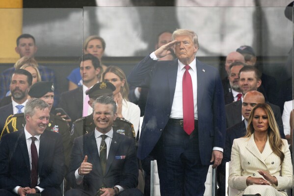 President Donald Trump salutes as attends a military parade commemorating the Army's 250th anniversary, coinciding with his 79th birthday, Saturday, June 14, 2025, in Washington, as Secretary of the Army Daniel Driscoll, Defense Secretary Pete Hegseth, and first lady Melania Trump, watch. (AP Photo/Julia Demaree Nikhinson)