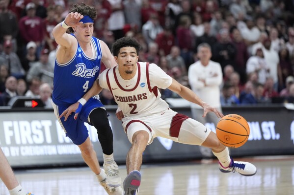 Washington State's Myles Rice (2) and Drake's Conor Enright (4) chase a loose ball during the first half of a first-round college basketball game in the NCAA Tournament Thursday, March 21, 2024, in Omaha, Neb. (AP Photo/Charlie Neibergall)