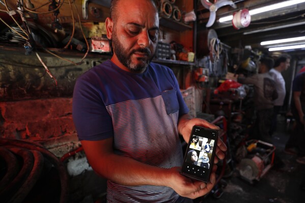 Mohammed Khier Qalaji, the brother of Firas Qalaji a Syrian man who died during the floods in the Libyan city of Derna, shows through his mobile phone the children of his brother who were also killed with their father, in Damascus, Syria, Saturday, Sept. 16, 2023. Firas Qalaji, 45, a car mechanic, had been living in Libya since 2000 and his wife Rana Khateeb and their six children were to be buried in Libya, the family said in a statement. (AP Photo/Omar Sanadiki)