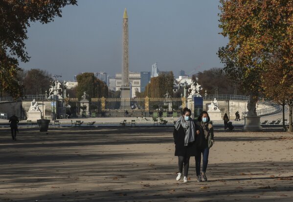 Women wearing face masks as a precaution against the coronavirus walk through the Tuileries garden in Paris, Friday, Nov. 6, 2020. The French government is supplying quick virus tests to nursing homes around the country, amid sharply rising numbers of virus infections and deaths in care homes in recent weeks. Arc de Triomphe and Obelisk in the background. (AP Photos/Michel Euler)