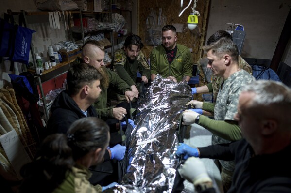 Ukrainian military medics of the 47th Brigade shift an injured comrade to a stretcher at the field hospital in Avdiivka direction, Donetsk region, Ukraine, Friday, May 10, 2024. (Ǻ Photo/Evgeniy Maloletka)