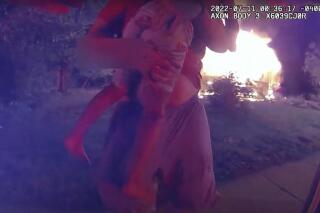 In this image taken from police bodycam video on July 11, 2022 and provided by the Lafayette, Ind., Police Department, Nick Bostic, 25, of Lafayette rescues a 6-year-old girl from a house fire in Lafayette, Ind.  Bostic punched out a second-floor window and jumped out with the girl in his arms, sustaining multiple injuries, while the girl suffered a minor cut to her foot. He rescued four others from the house before that. (Lafayette Police Department via AP)