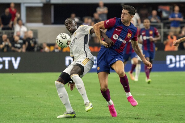 FILE - Real Madrid defender Ferland Sinna Mendy, left, and FC Barcelona forward Robert Lewandowski (9) compete for the ball during the first half of a Champions Tour soccer match, Saturday, July 29, 2023 at AT&T Stadium in Arlington, Texas. Real Madrid faces one last stumbling block on its waltz toward the Spanish league title. Barcelona is coming to town on Sunday, April 21, 2024. Madrid is eight points ahead of Barcelona going into the clasico match. (AP Photo/Jeffrey McWhorter, File)
