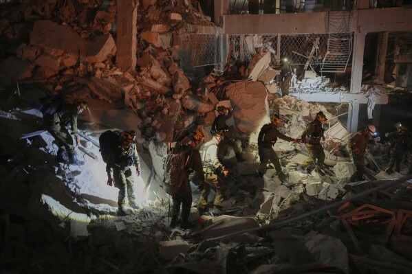 Israeli security forces inspect a destroyed building that was hit by a missile fired from Iran, near Tel Aviv, Israel, early Sunday, June 15, 2025. (AP Photo/Ohad Zwigenberg)
