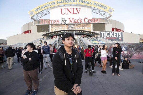 Oscar Hernandez, center, a student at the University of Nevada, Las Vegas, waits for a bus to take him off campus after a fatal shooting on Wednesday, Dec. 6, 2023, in Las Vegas.  (Steve Marcus/Las Vegas Sun via AP)