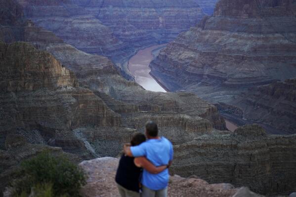 Alyssa Chubbuck, left, and Dan Bennett embrace while watching the sunset at Guano Point overlooking the Colorado River on the Hualapai reservation Monday, Aug. 15, 2022, in northwestern Arizona. In November 1922, seven land-owning white men brokered a deal to allocate water from the Colorado River, which winds through the West and ends in Mexico. During the past two decades, pressure has intensified on the river as the driest 22-year stretch in the past 1,200 years has gripped the southwestern U.S. (AP Photo/John Locher)