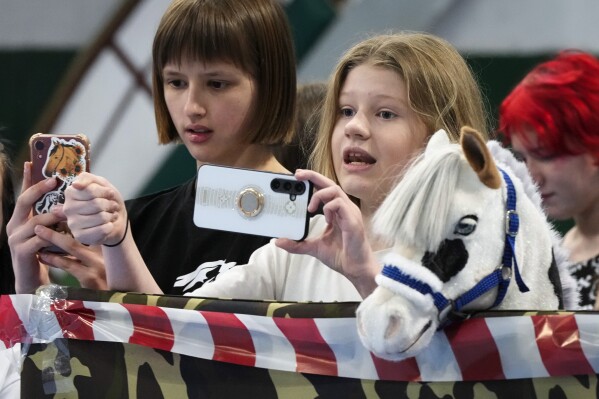 Participants watch races of their competitors during a Hobby horsing competition in St. Petersburg, Russia, on Sunday, April 21, 2024. Several dozen kids, 48 girls and one boy, from first-graders to teenagers gathered in a gymnasium in northern St. Petersburg, Russia's second largest city, for a hobby horsing competition. (AP Photo/Dmitri Lovetsky)