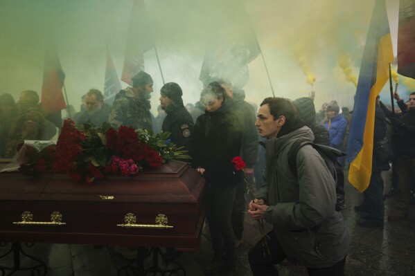 A man gives his last salute to a Ukrainian officer Pavlo Vedybida aka "Obolonchik" during funeral ceremony on Independence square in Kyiv, Ukraine, Saturday, Nov. 30, 2024. (AP Photo/Evgeniy Maloletka)
