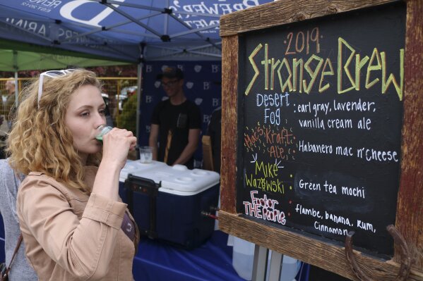 In this photo taken May 18, 2019, a woman tastes a green tea mocha beer at the Strange Brew Festival in Reno, Nev. As craft breweries have boomed, competition for attention has intensified and that has a lot of brewers looking for ways to differentiate themselves by introducing strange new flavors.   (AP Photo/Haven Daley)