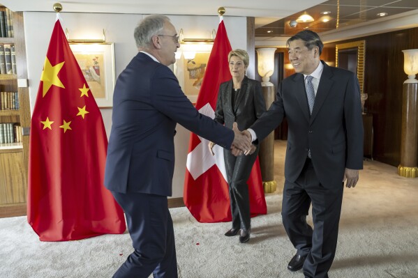 Switzerland's Economy Minister Federal Councillor Guy Parmelin, left, shakes hands with Chinese Vice Premier He Lifeng, right, next to Switzerland's President Karin Keller-Sutter, center, during a bilateral meeting between Switzerland and China, in Geneva, Switzerland, on Friday, May 9, 2025. (Martial Trezzini/Keystone via AP, Pool)