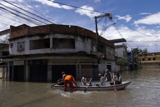 Firefighters evacuate residents through a flooded street after deadly rainfall in Belford Roxo, Brazil, Monday, Jan. 15, 2024. (AP Photo/Bruna Prado)