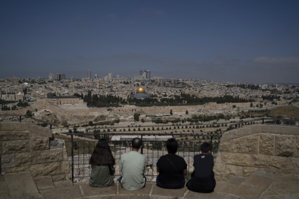 People visit the Mount of Olives overlooking the Dome of the Rock at the Al Aqsa Mosque compound in the Old City of Jerusalem, Friday, April 19, 2024. Tensions have been high since the Saturday assault on Israel amid its war on Hamas in the Gaza Strip and its own strikes targeting Iran in Syria. (AP Photo/Leo Correa)