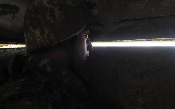 An Ethnic Armenian soldier looks through the gap toward Azerbaijan's positions from a dugout at a fighting position on the front line, during a military conflict against Azerbaijan's armed forces in the separatist region of Nagorno-Karabakh, Wednesday, Oct. 21, 2020. Armenia's prime minister has urged citizens to sign up as military volunteers to help defend the country amid the conflict with Azerbaijan over the disputed territory of Nagorno-Karabakh as intense fighting has raged for a fourth week with no sign of abating. (AP Photo)