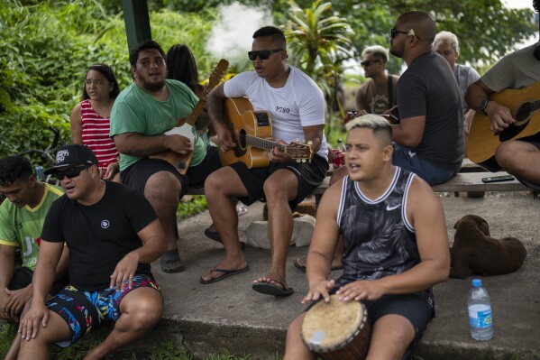 A group plays music together by the side of the road in Teahupo'o, Tahiti, French Polynesia, Tuesday, Jan. 16, 2024. (AP Photo/Daniel Cole)