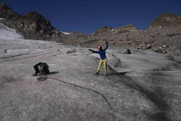 Glaciologist Violeta Lauria from the Austrian Academy of Sciences measures the Jamtalferner Glacier near Galtuer, Austria, Wednesday, Sept. 6, 2023. (AP Photo/Matthias Schrader)